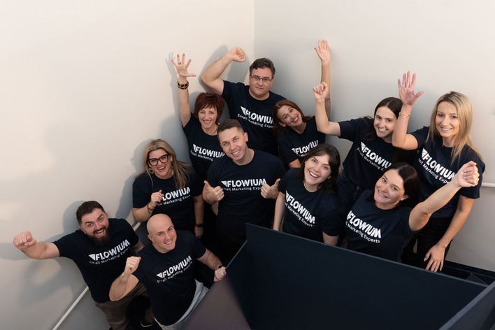 The Flowium team is smiling and waving.