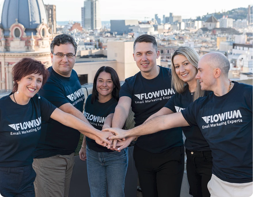 Six team members wearing Flowium T-shirts standing together on a rooftop, smiling and placing their hands together.